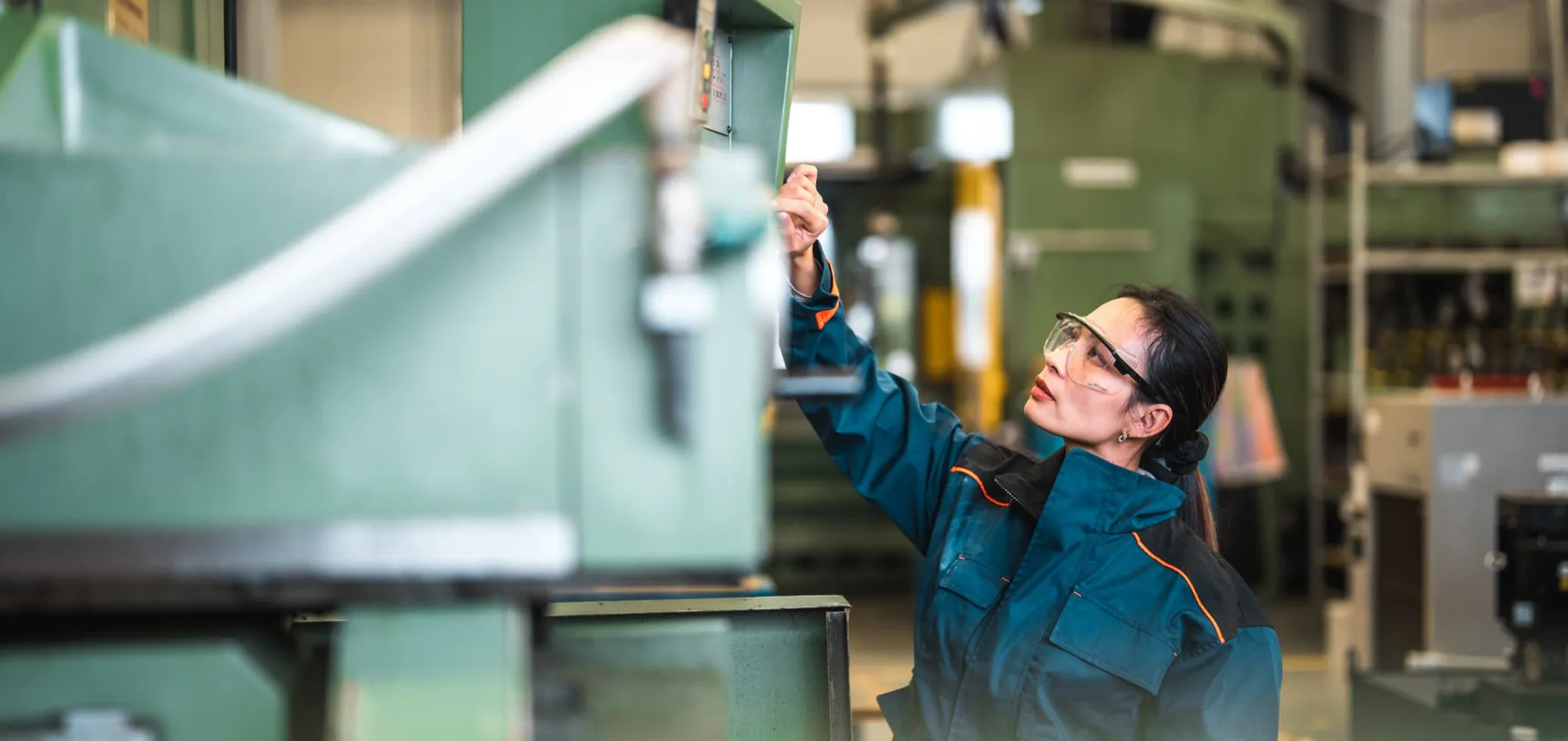 Een vrouw in werkkledij inspecteert een machine